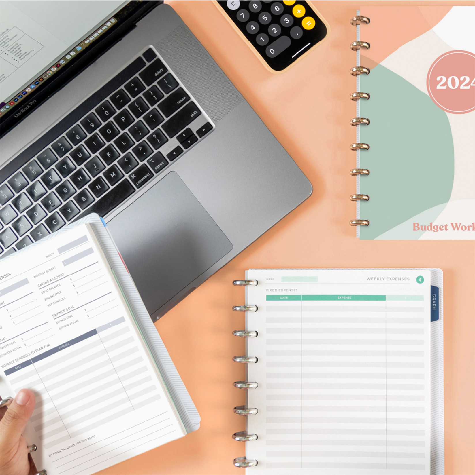 Person holding a Budget Lifestyle Notebook over a laptop Person holding a Budget Lifestyle Notebook over a laptop