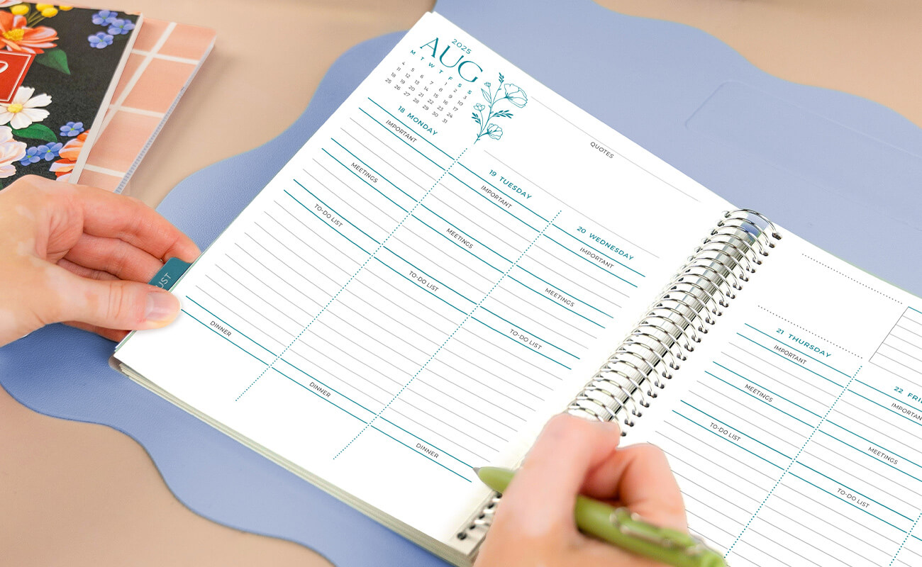 Person writing in the month of August of their Soft Florals Weekly Planner. Person writing in the month of August of their Soft Florals Weekly Planner.