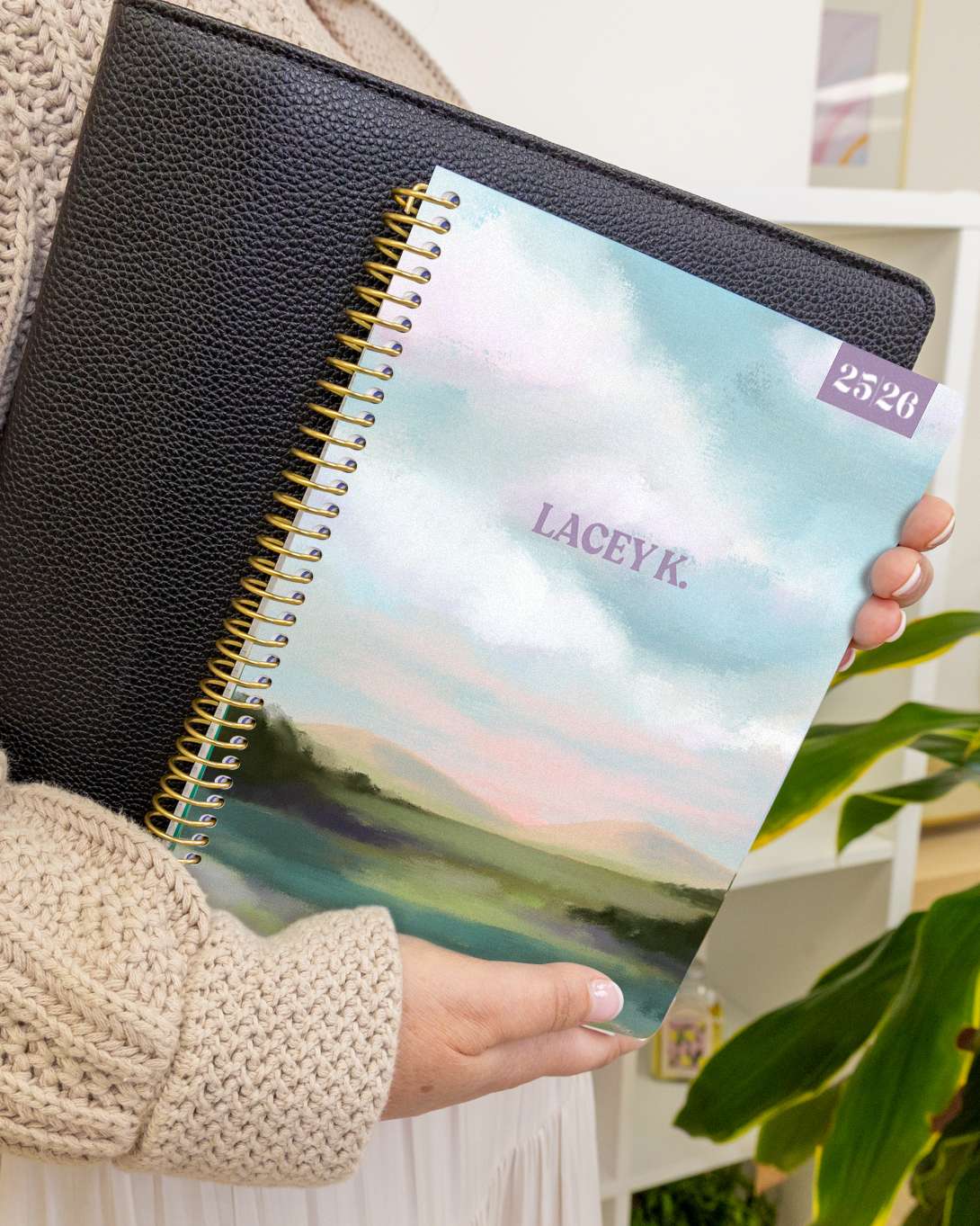 Person holding a planner and planner folio showing a landscape scene. Person holding a planner and planner folio showing a landscape scene.