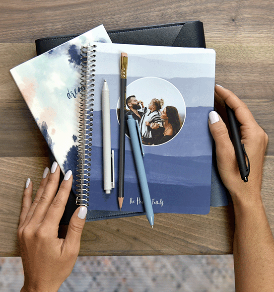 Coiled planner with pens on top of blue ombre cover