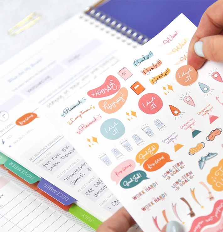 Someone putting Goal Setting Stickers on their planner Someone putting Goal Setting Stickers on their planner