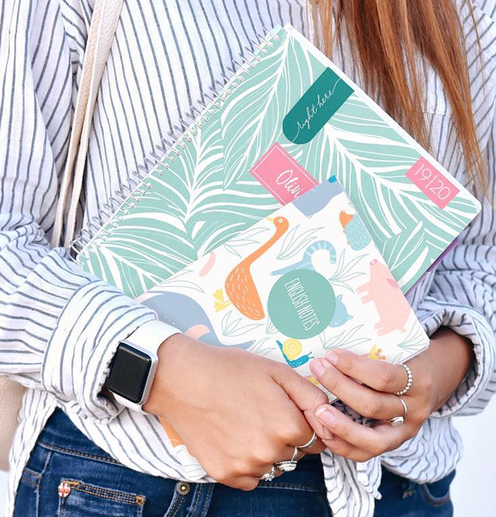 Woman holding planner and journal with customized covers.