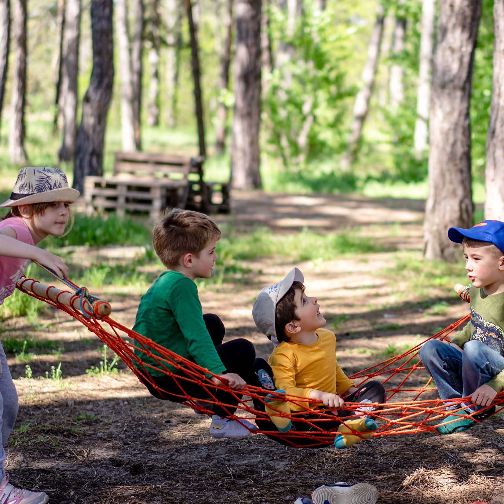 4 kids playing in a hammock in the woods