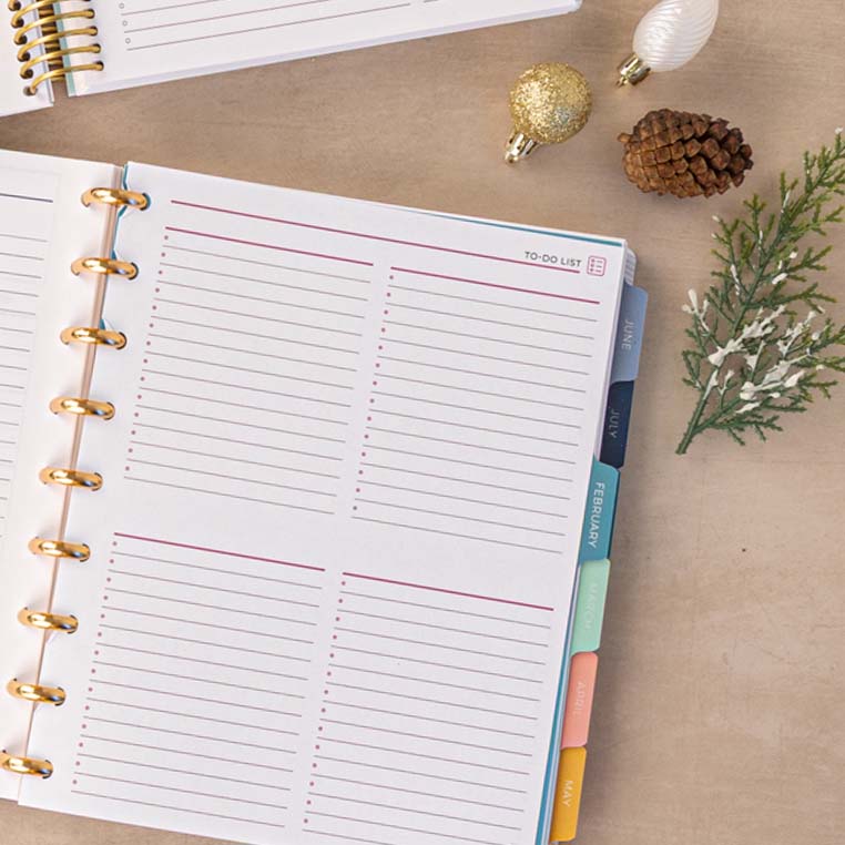 Handmade Plum Paper custom planner with gold disc binding on a festive holiday desk surrounded by ornaments, pinecones, and greenery — a beautiful personalized stationery gift and custom planner for 2026. Handmade Plum Paper custom planner with gold disc binding on a festive holiday desk surrounded by ornaments, pinecones, and greenery — a beautiful personalized stationery gift and custom planner for 2026.