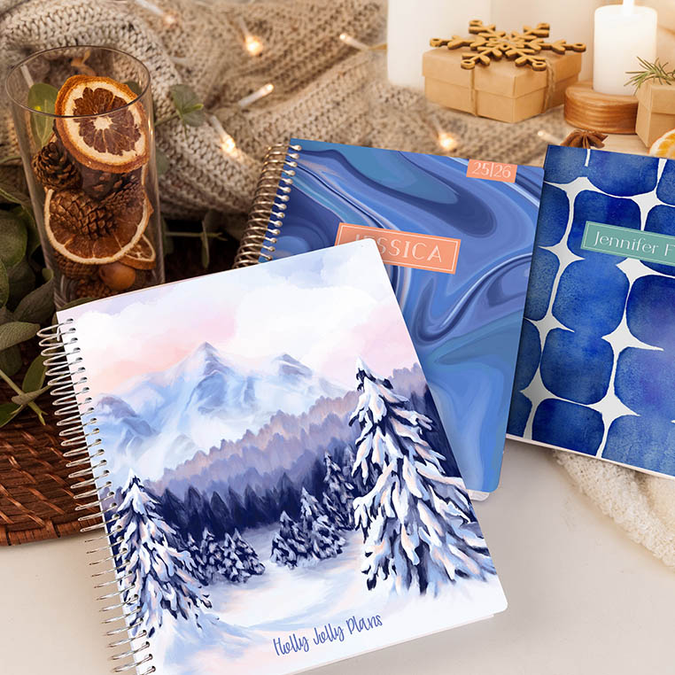 Stack of Plum Paper handmade planners featuring winter cover patterns — customizable 2026 planners with blue watercolor, snow mountain, and modern geometric designs for personalized holiday gifts. Stack of Plum Paper handmade planners featuring winter cover patterns — customizable 2026 planners with blue watercolor, snow mountain, and modern geometric designs for personalized holiday gifts.