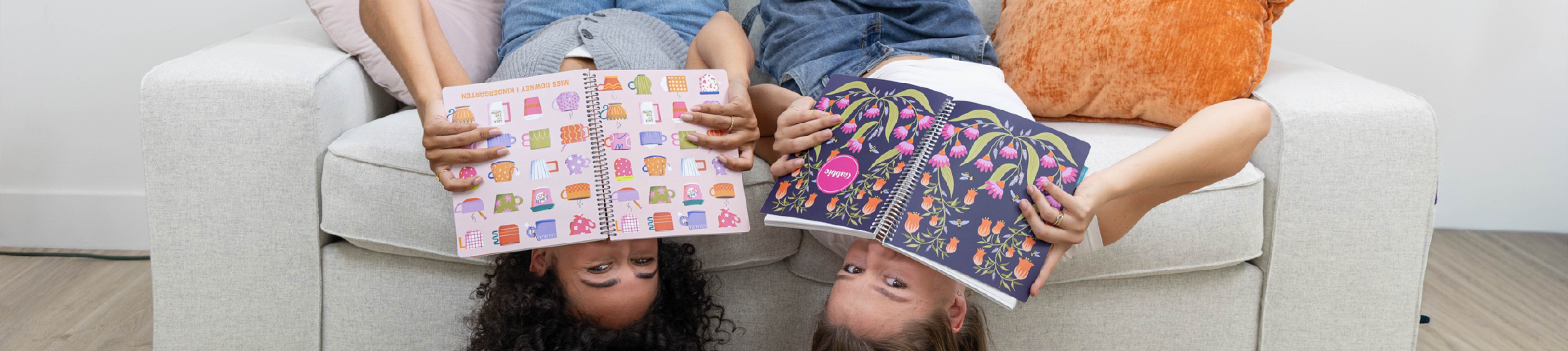 two women, with planners, lounging on a couch