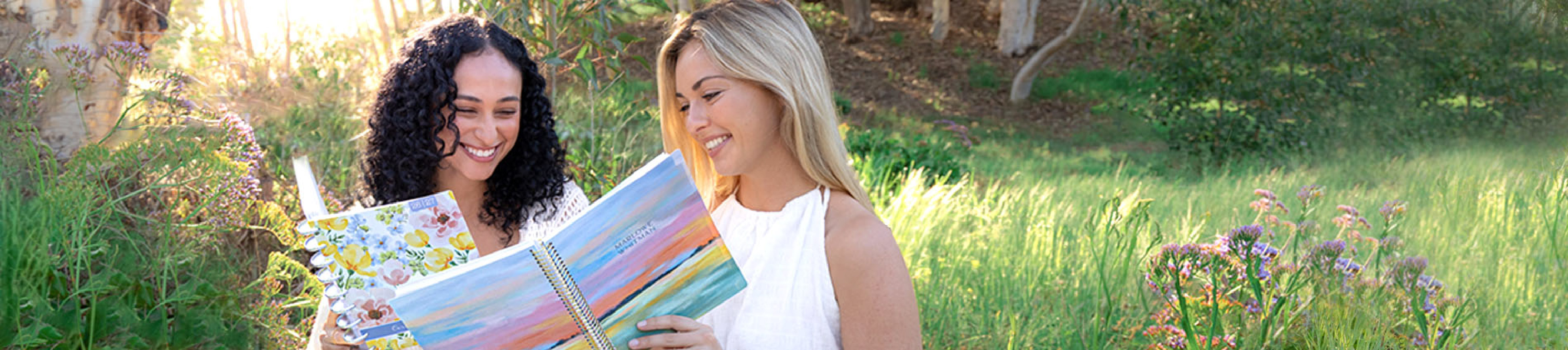 Two women reviewing planners together in a bright spring setting during the spring planner sale Two women reviewing planners together in a bright spring setting during the spring planner sale
