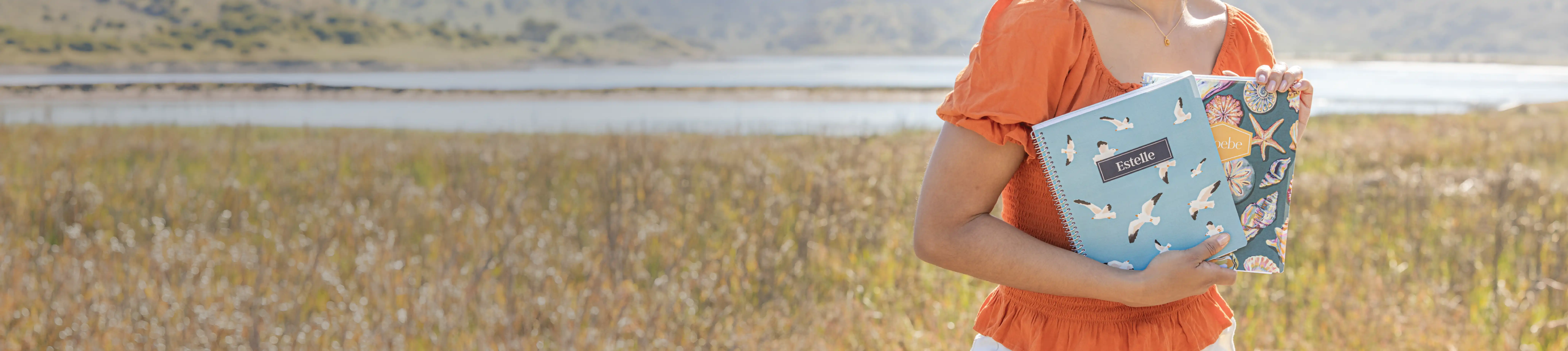 Woman holding two planners while standing in a field Woman holding two planners while standing in a field